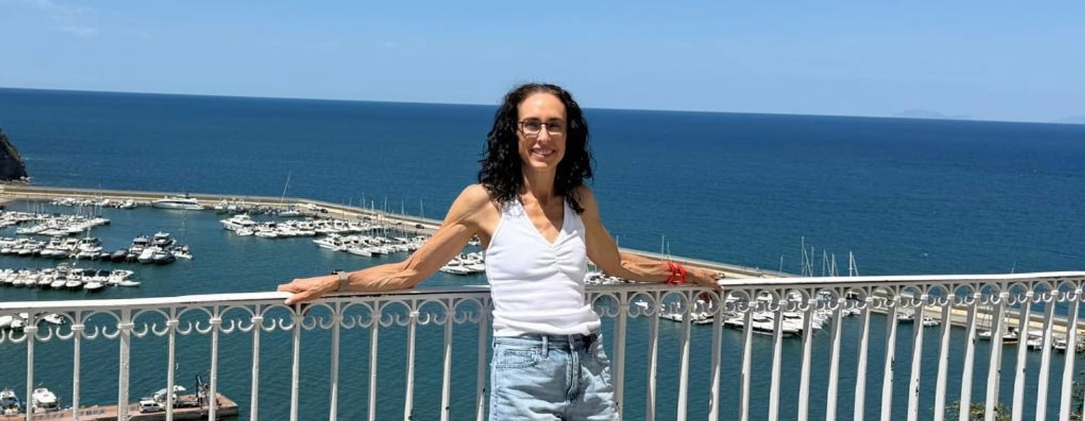 Breast cancer patient Jessica on a trip in Italy posing at a seaside viewpoint